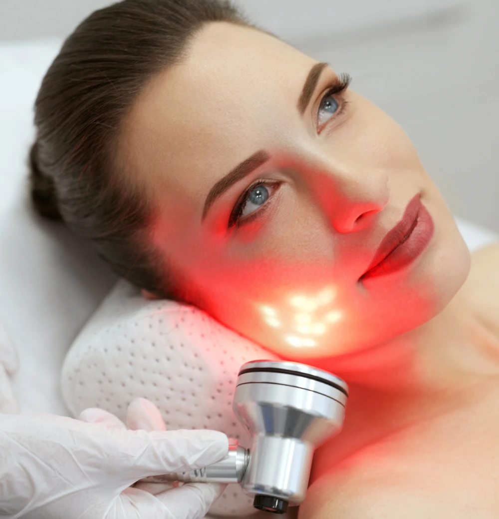 Close-up of woman receiving targeted red light therapy facial treatment for skin rejuvenation at ReNuYou wellness studio